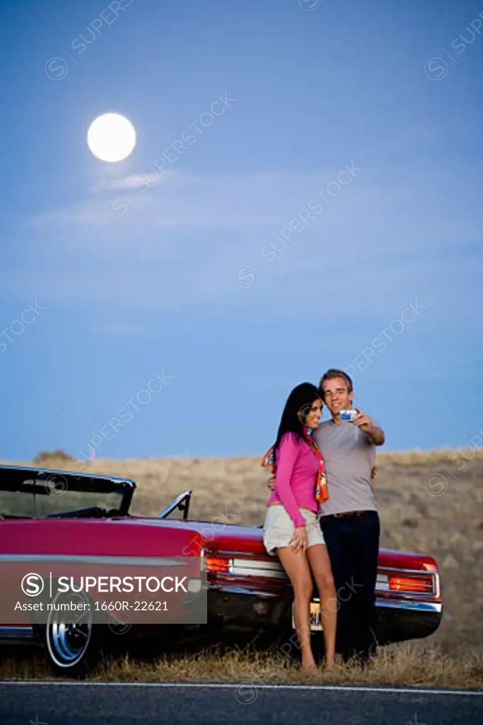 man and woman next to a red convertible