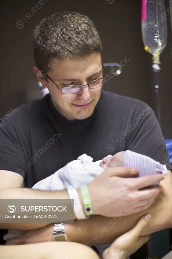 Father carrying his newborn baby girl in a hospital ward