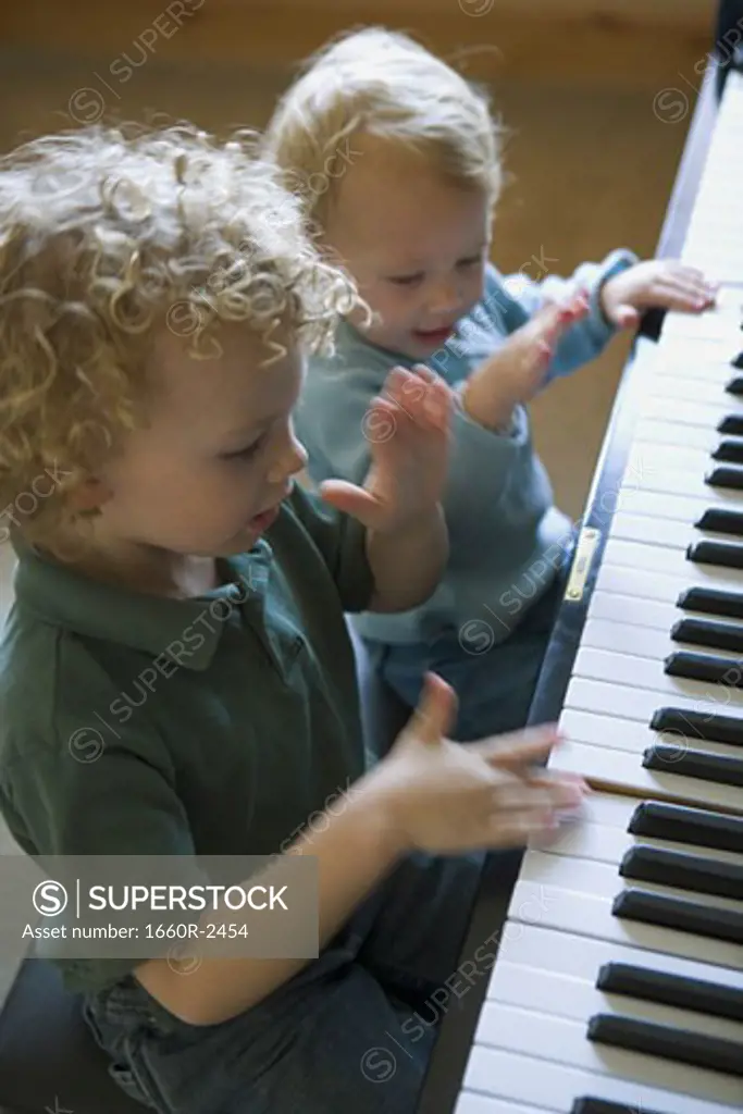 High angle view of a brother and his sister playing piano