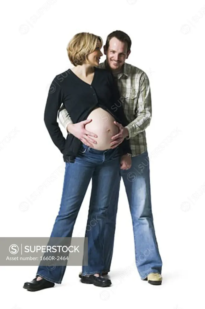 Portrait of a mid adult man touching his pregnant wife's abdomen