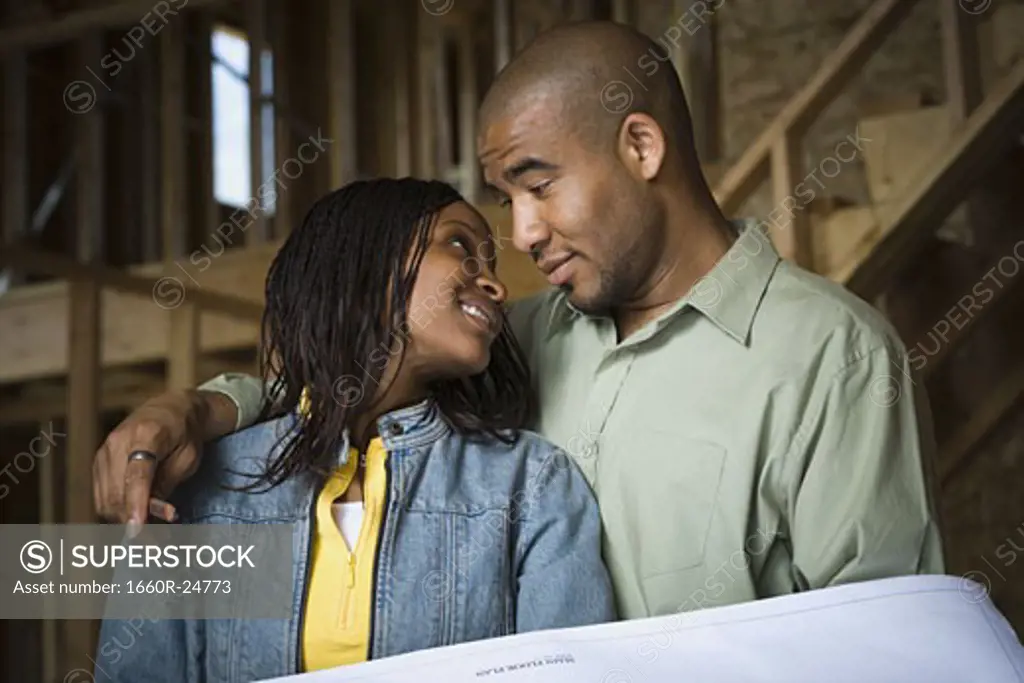 Portrait of a young couple smiling in a home that is being constructed