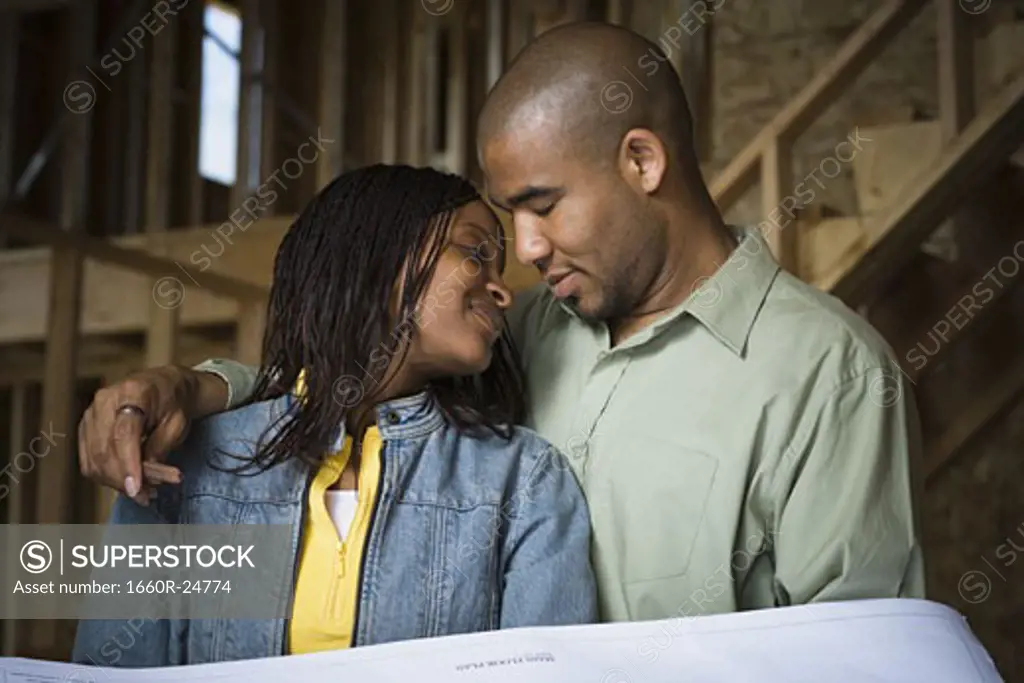 Portrait of a young couple smiling in a home that is being constructed
