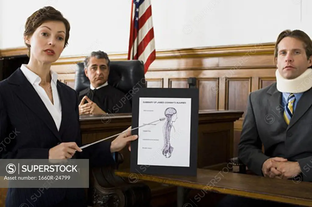 Female lawyer pointing at an exhibit in front of a judge and a victim