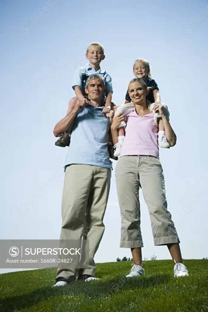 Portrait of parents carrying their two children on their shoulders