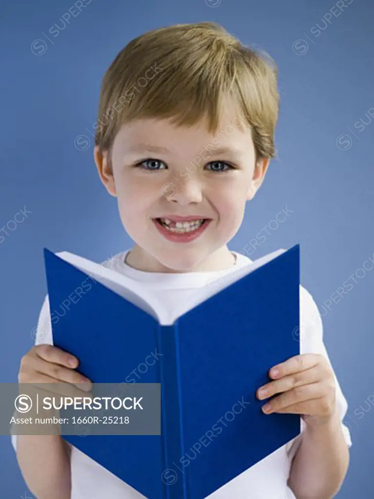 Boy reading hardcover book smiling