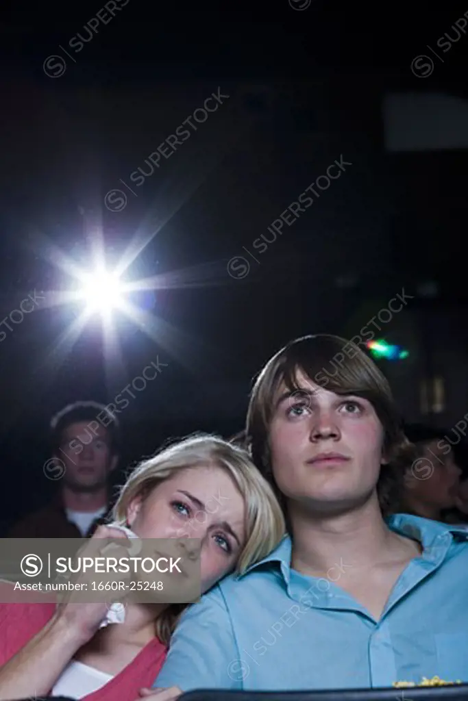 Crying girl and smiling boy watching movie at theater