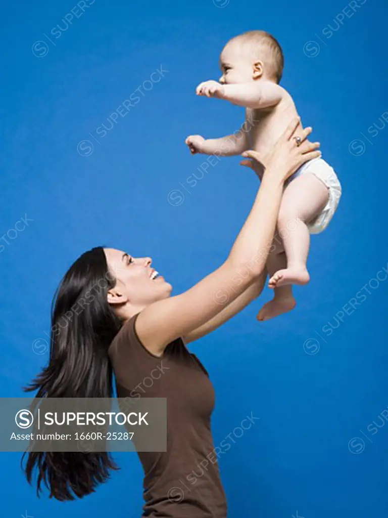 Woman lifting baby in air smiling