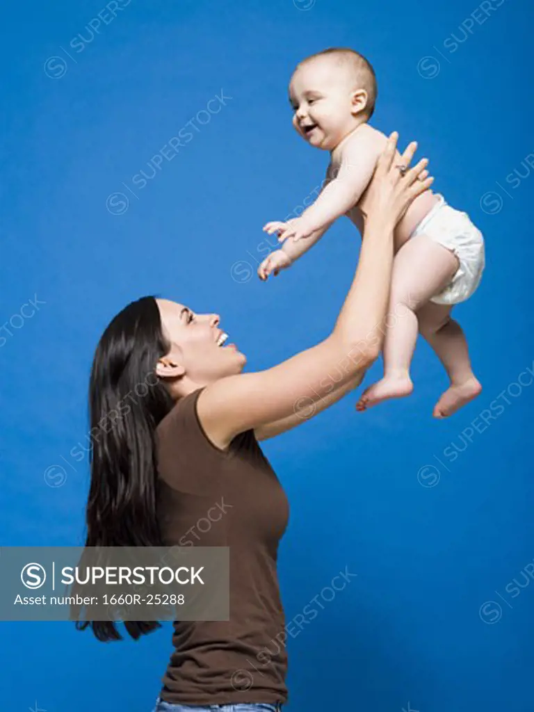 Woman lifting baby in air smiling