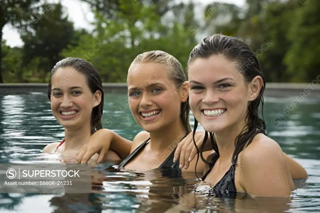 Portrait of three teenage girls smiling in a swimming pool and smiling