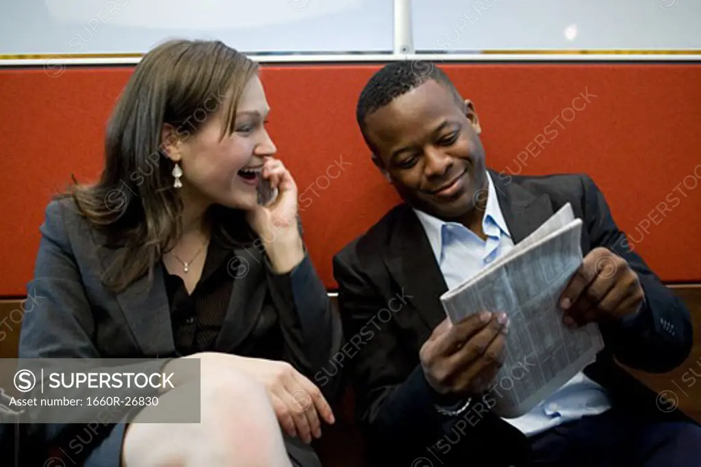 Businessman and a businesswoman reading a newspaper