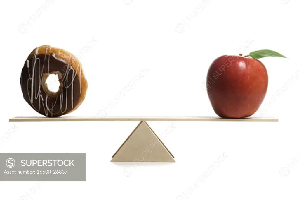 Close-up of a donut and an apple on a seesaw