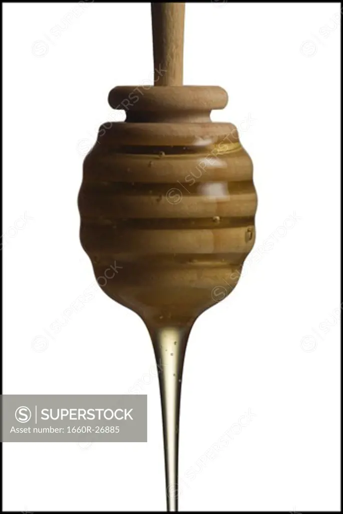 Drop of honey falling from a honey dipper