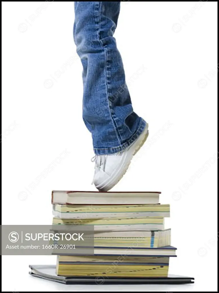 Low section view of a girl standing on a stack of books