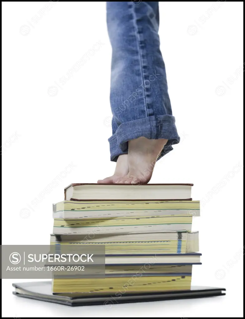 Low section view of a girl standing on a stack of books