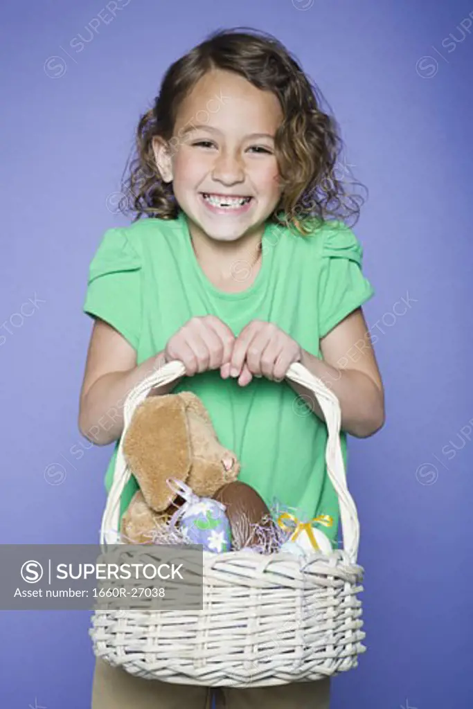 Portrait of a girl holding Easter bunnies and Easter eggs in a wicker basket