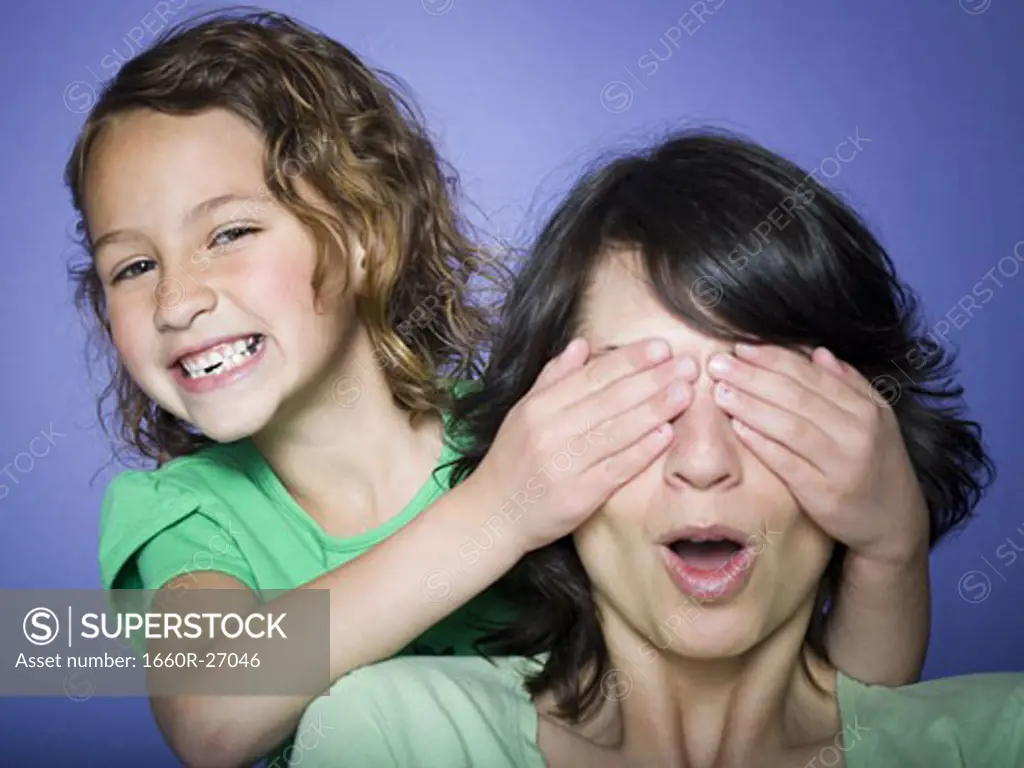 Close-up of a girl covering her mother's eyes