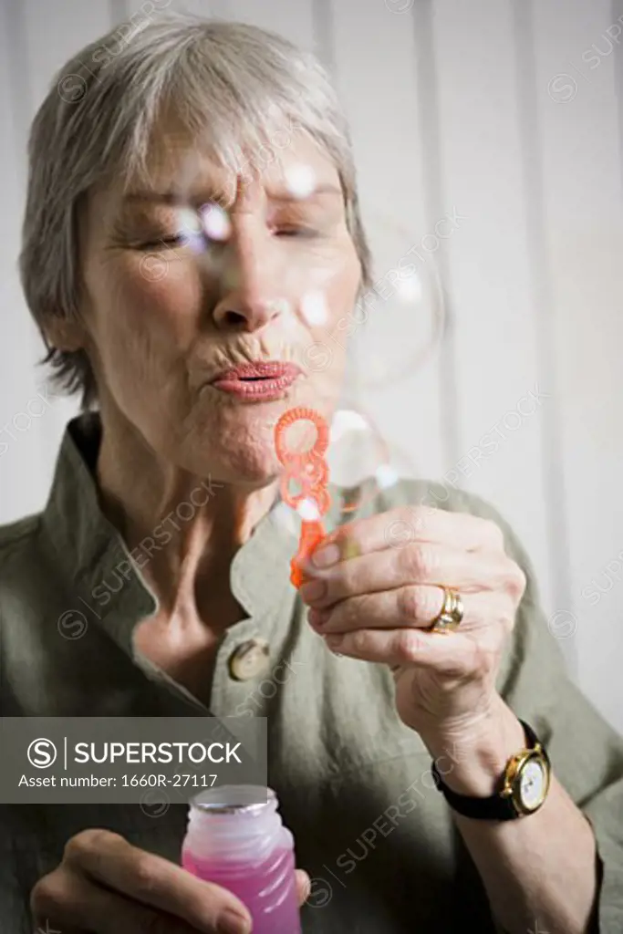 Portrait of an elderly woman blowing bubbles with a bubble wand