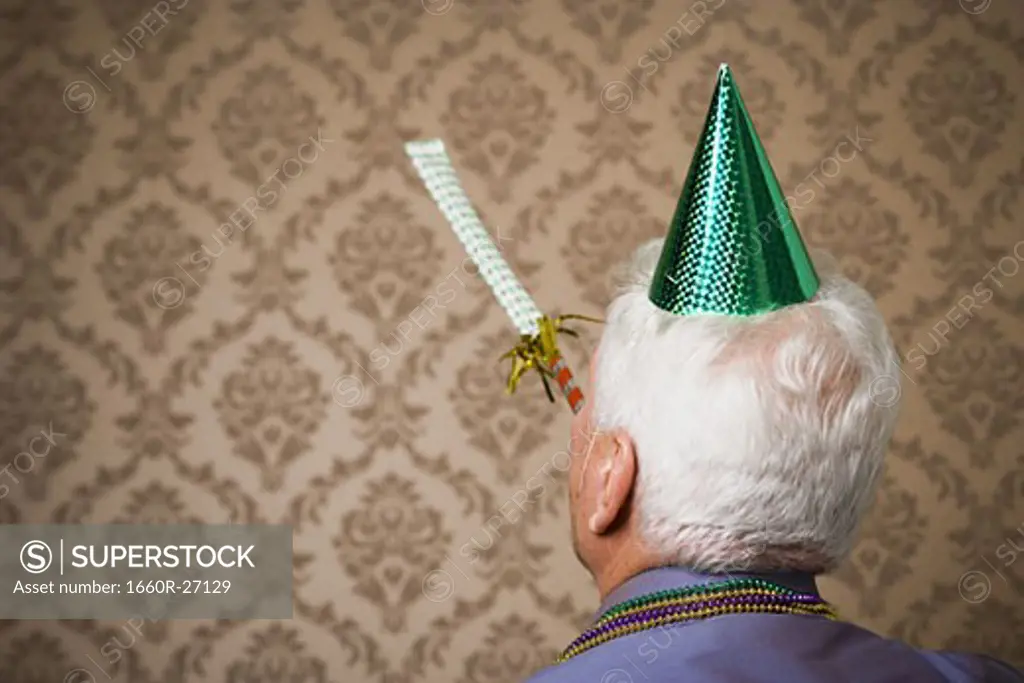 Rear view of an elderly man wearing a birthday hat