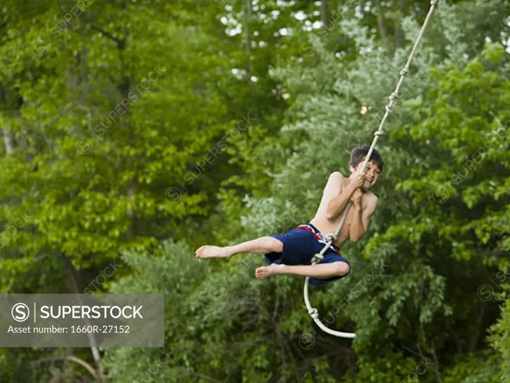 Portrait of a boy swinging on a rope