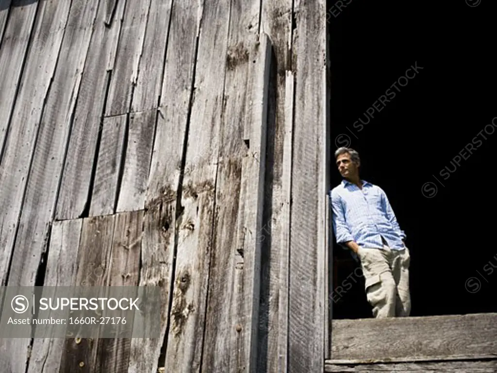 Low angle view of a man leaning against a wooden wall