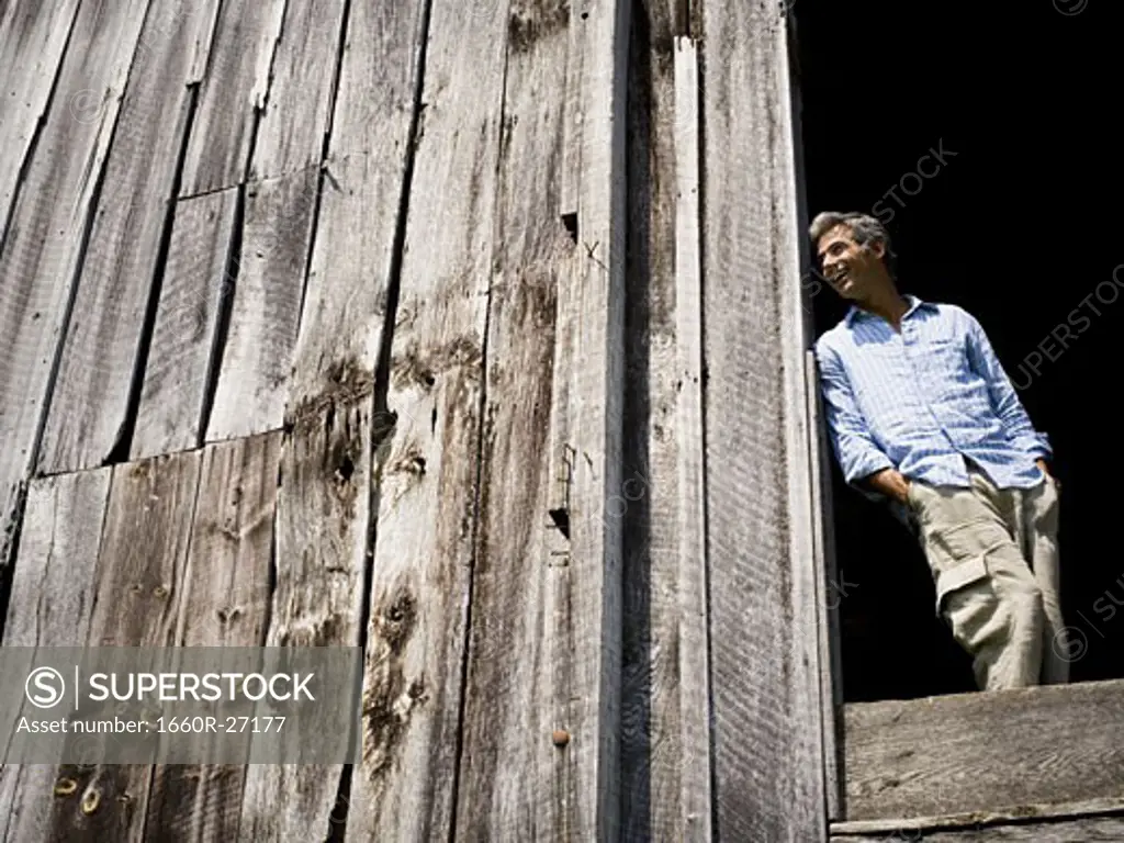 Low angle view of a man leaning against a wooden wall