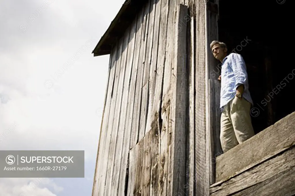 Low angle view of a man leaning against a wooden wall