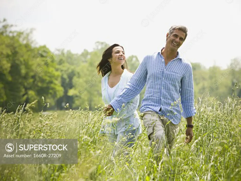man and a woman holding hands in a field