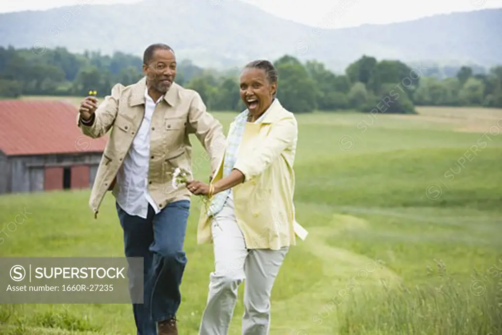Senior woman and a senior man running in a field