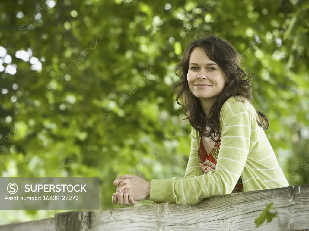 Portrait of a woman leaning on a wooden fence