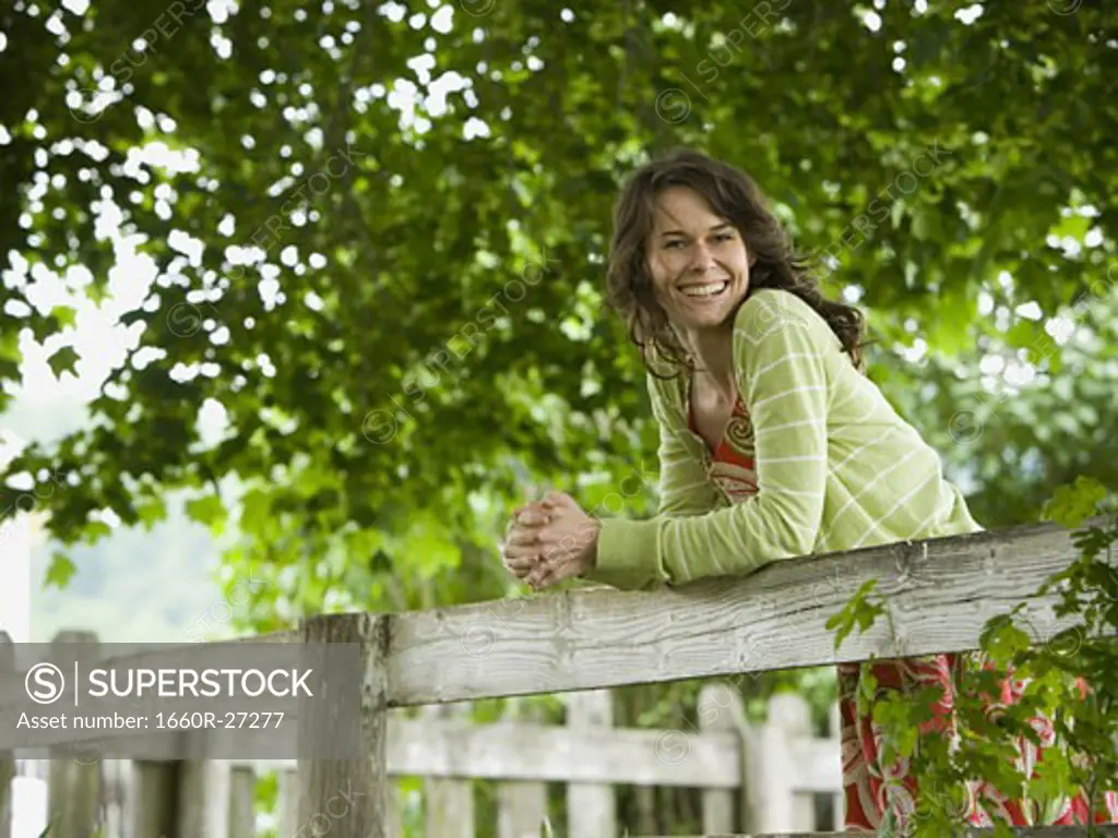 Portrait of a woman leaning on a wooden fence