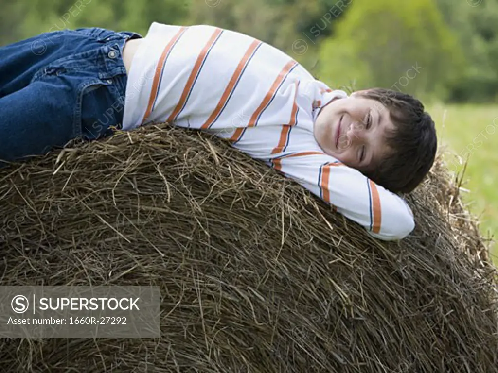 Portrait of a boy lying on a hay bale