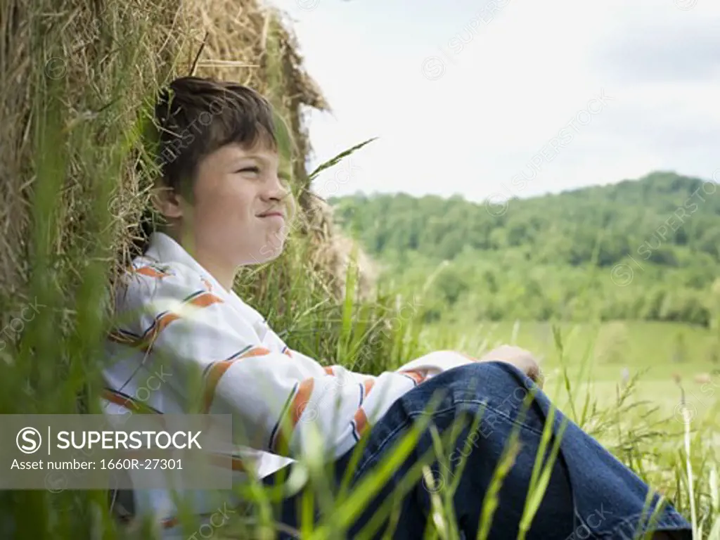 Portrait of a boy sitting against a hay bale