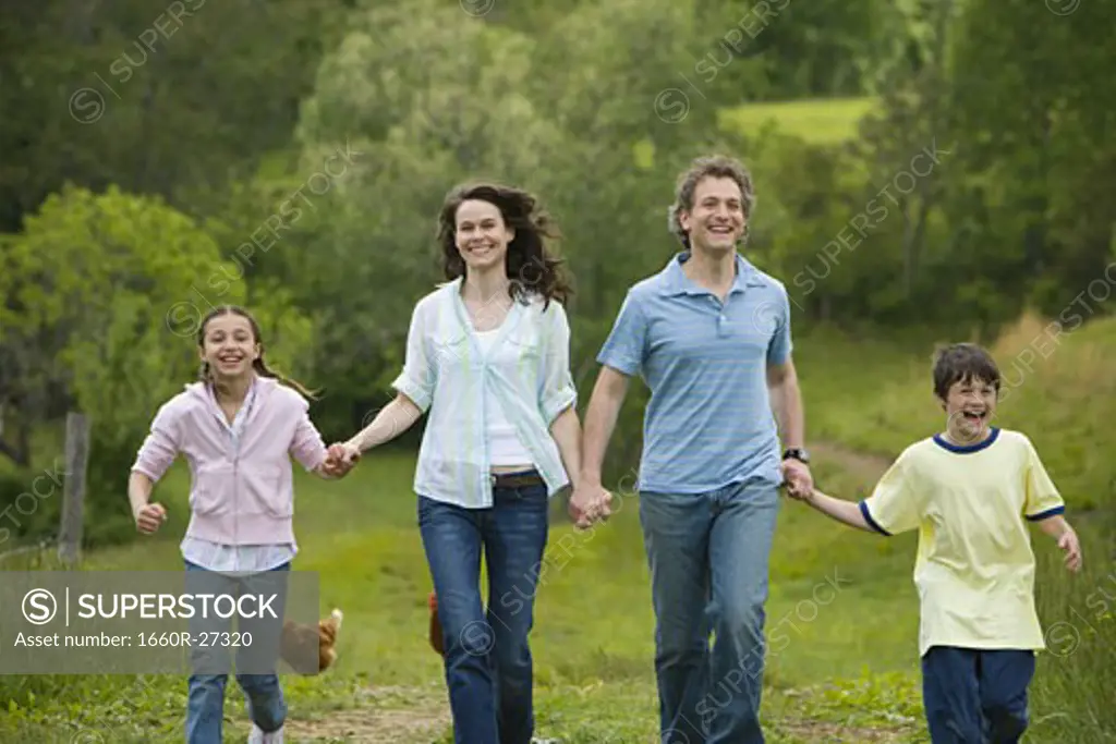 woman and a man with their son and daughter running in a field