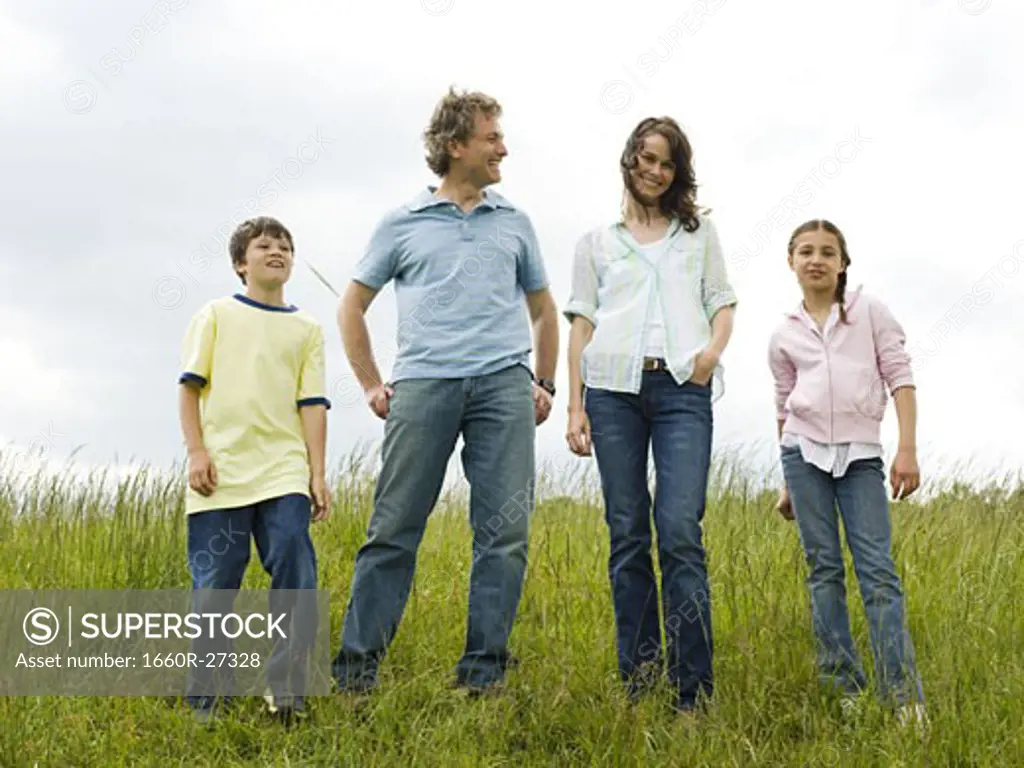 woman and a man standing with their son and daughter in a field