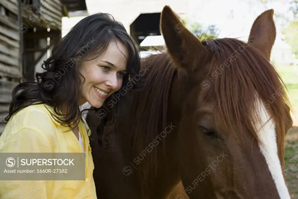 Portrait of a woman and a horse standing in front of a barn
