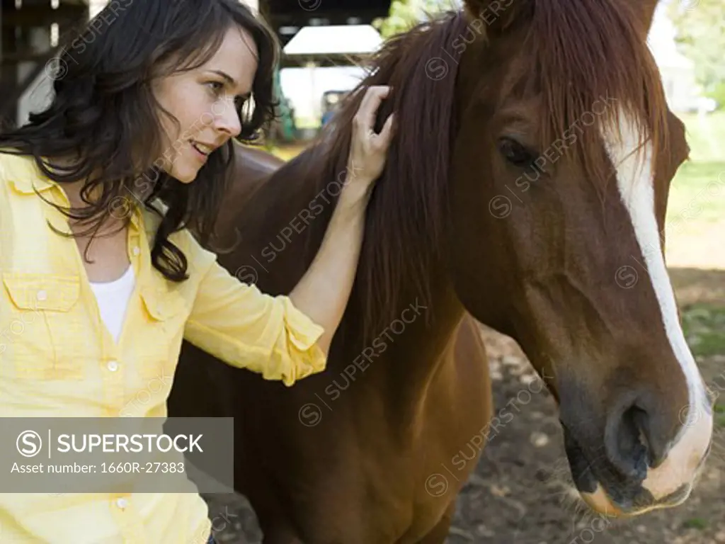 Portrait of a woman and a horse standing in front of a barn