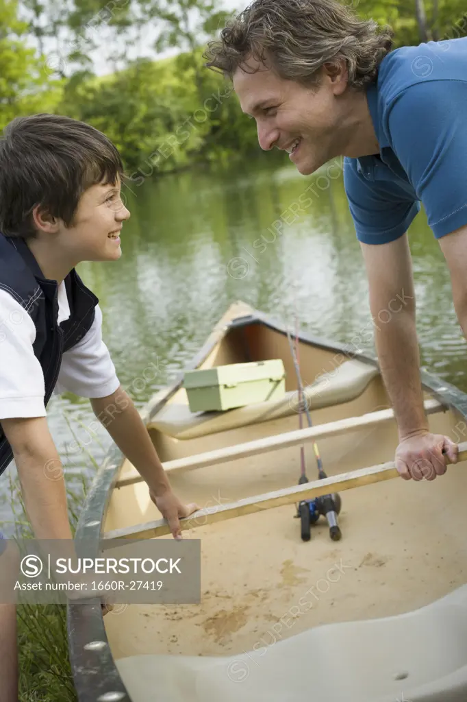 Profile of a man and his son bending forward over a canoe