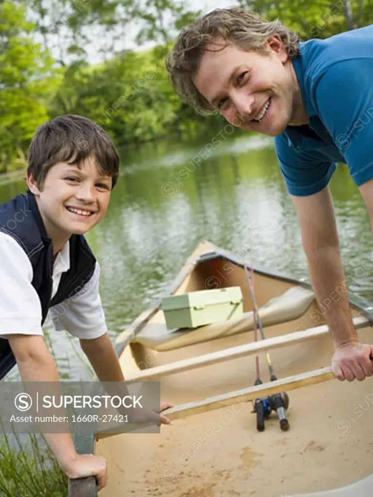 Portrait of a man and his son bending forward over a canoe