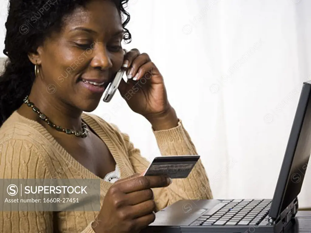 Profile of a mature woman talking on a mobile phone and holding a credit card