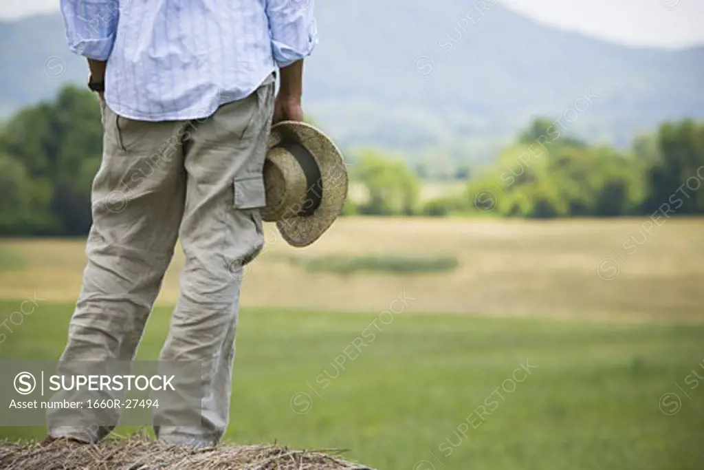Low section view of a man standing on a hay bale