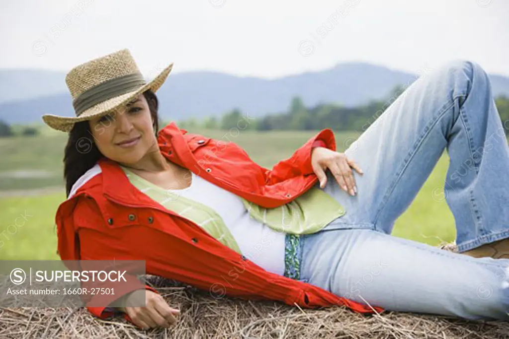 Portrait of a woman lying on a hay bale