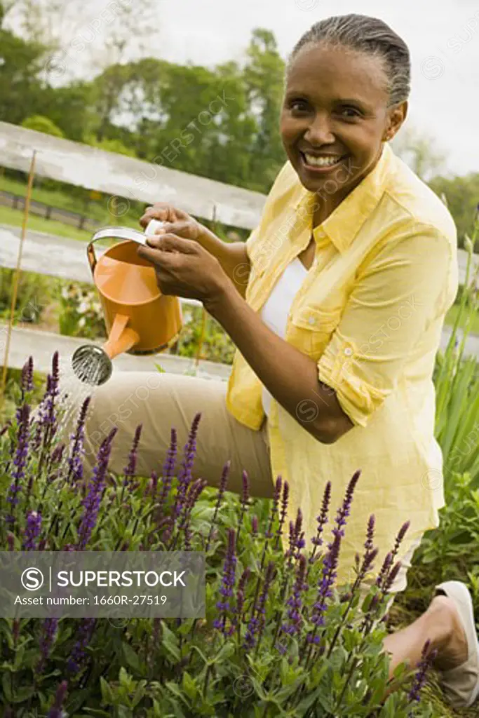 Portrait of a senior woman watering flowers
