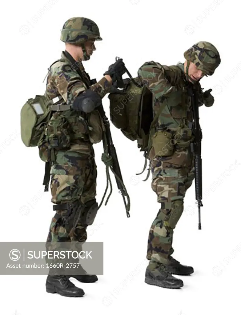 Side profile of an army soldier adjusting the backpack of another soldier