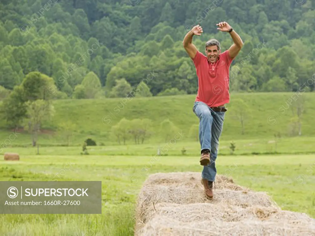 Portrait of a man jumping on a hay bale