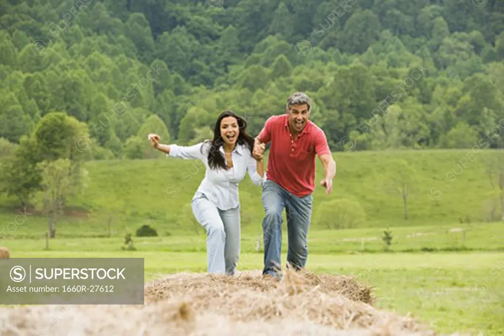 Portrait of a man and a woman running on hay bales