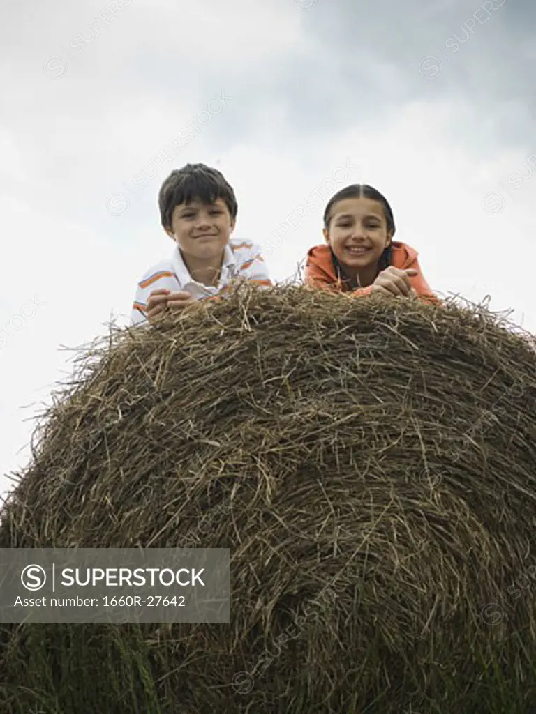 Portrait of a boy and a girl lying on top of a haystack