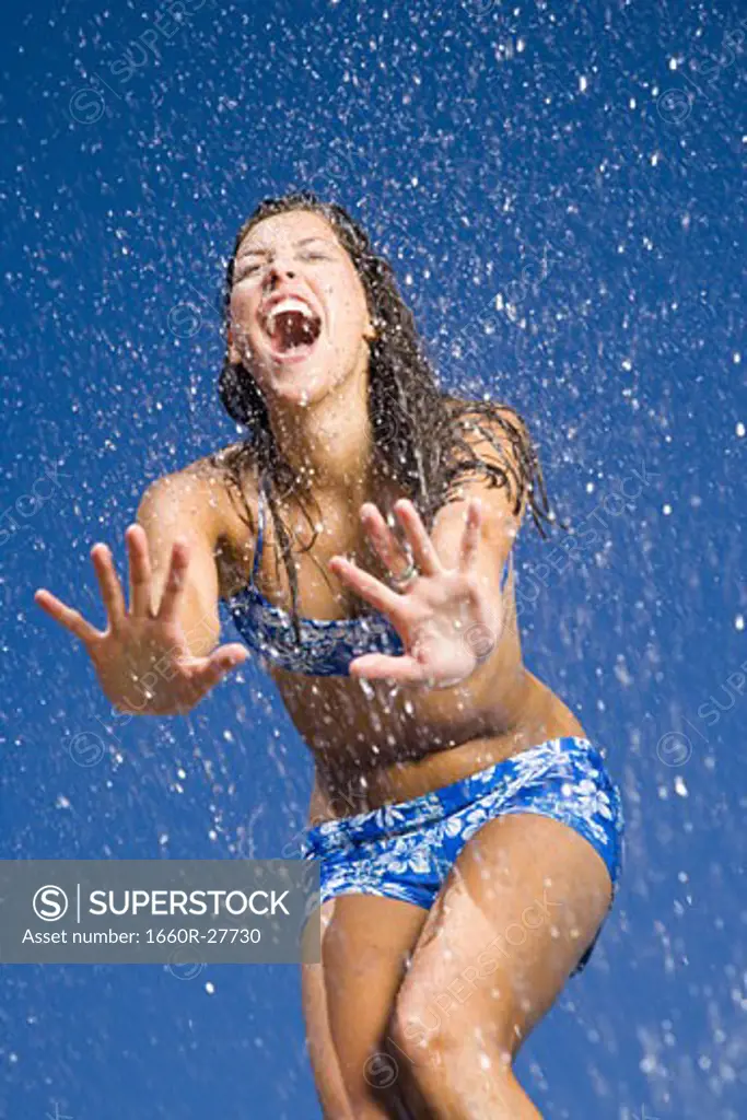 Close-up of a young woman getting sprayed with water