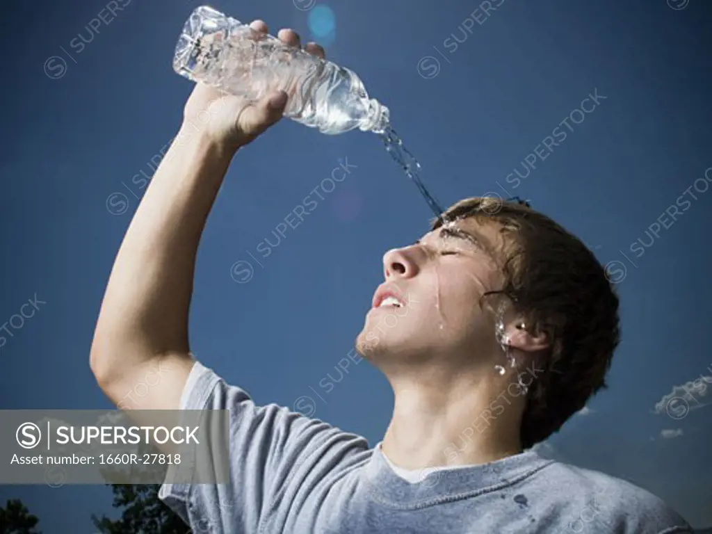 Close-up of a teenage boy pouring water over his head