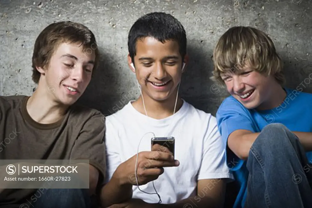 Close-up of three teenage boys looking at an MP3 player