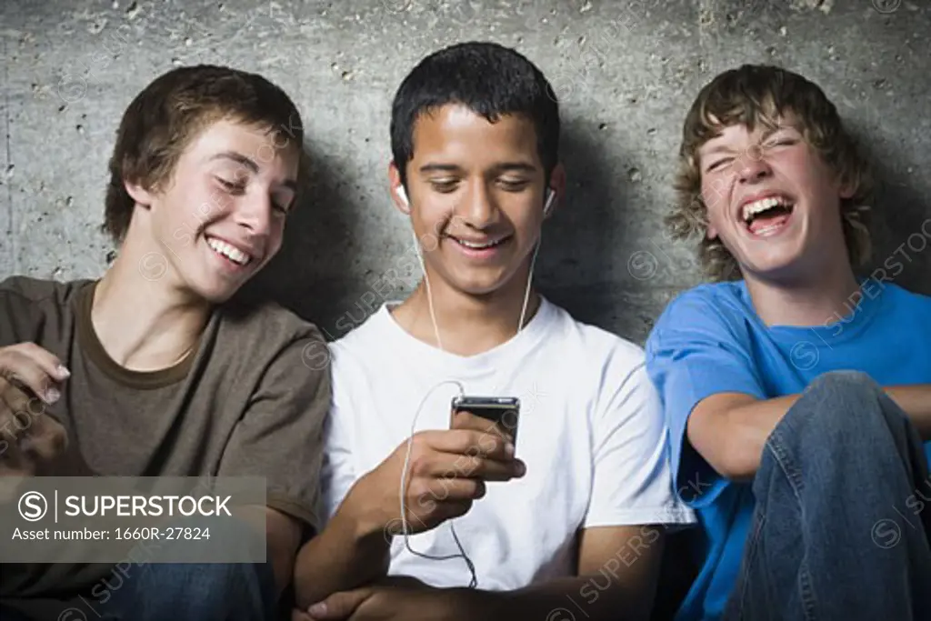 Close-up of three teenage boys looking at an MP3 player